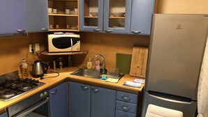 A compact kitchen with a gas stove, oven, microwave, sink, and a refrigerator. - Apartman Sever Hroncova (Kosice)
