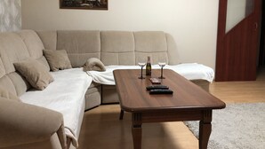 A living room with a beige sofa, a wooden coffee table, and a painting on the wall. - Apartman Sever Hroncova (Kosice)