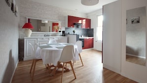 Eine moderne Küche mit roten Schränken, ein weißer Essbereich mit Tisch und Stühlen und ein großes Spiegelbild über der Arbeitsplatte.