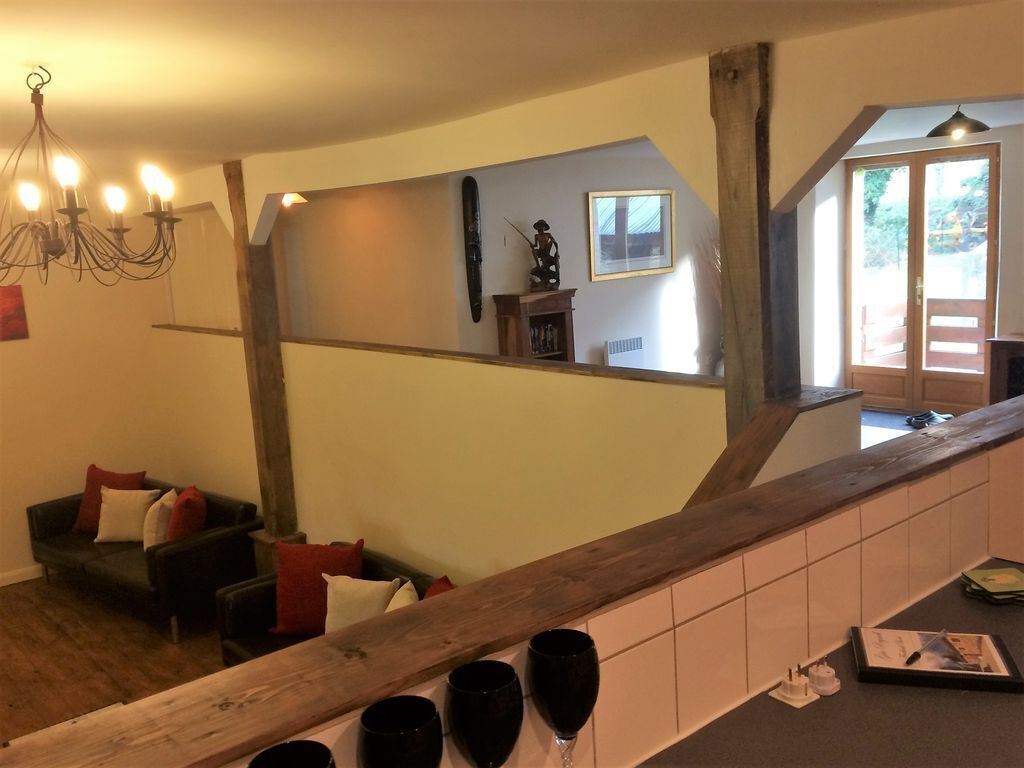 Ein Wohnzimmer mit einer Holztreppe, einer Chandelüster, einer Couch mit Kissen und einem Fenster mit Blick.