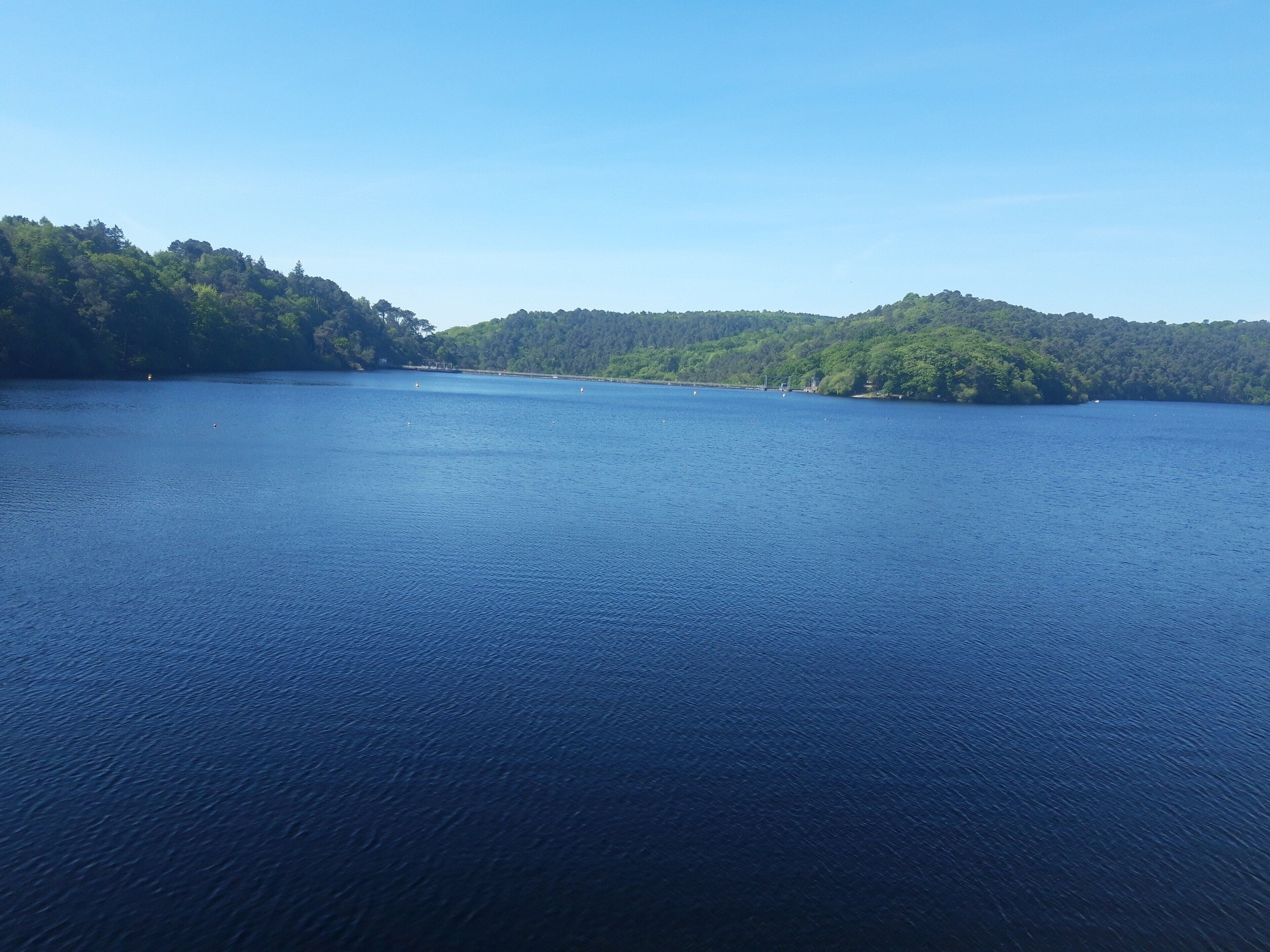 Une vaste étendue d’eau entourée de collines boisées.