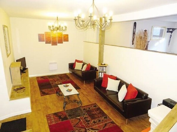 A living room with two sofas, a coffee table, and a chandelier. - Tranquil rural farmhouse gite with large garden and terrace (Plussulien)