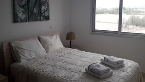Un dormitori amb llit, almoines, làmpada i obra d'art a la paret.