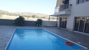 Una piscina rectangular amb superfície d'aigua blava i cristal·lina, envoltada per una zona pavimentada.