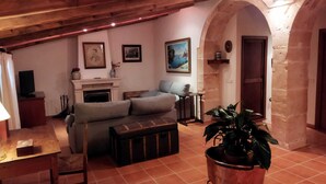 A cozy living room with a fireplace, a sofa, a coffee table, and a potted plant. - Cottage in the middle of nature (Petra)