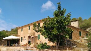 A two-story stone building with a balcony and a white umbrella. - Cottage in the middle of nature (Petra)
