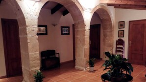 A spacious courtyard with tiled flooring, stone arches, and potted plants. - Cottage in the middle of nature (Petra)