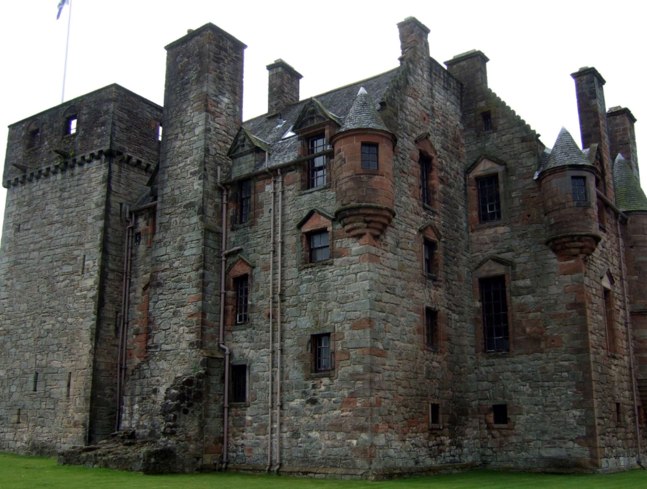 A historic stone castle with multiple towers and battlements, featuring a mix of stone and brick construction.
