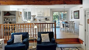 A spacious living area with a wooden staircase, a dining area, and a kitchen with white cabinets. - Cute, Quiet, Comfortable, Centrally Located, Outdoor Shower, Large Yard, BBQ (Nantucket)