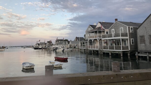 A waterfront property with a dock, boats, and a row of houses with balconies. - Cute, Quiet, Comfortable, Centrally Located, Outdoor Shower, Large Yard, BBQ (Nantucket)