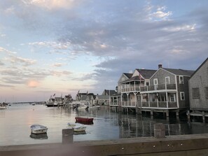 A waterfront property with a dock, boats, and a row of houses with balconies. - Cute, Quiet, Comfortable, Centrally Located, Outdoor Shower, Large Yard, BBQ (Nantucket)