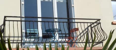 A balcony with a metal railing, a table, and two chairs.