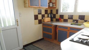 Een kleine keuken met houten kastjes, een spoelbak en een fornuis.