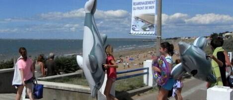 A coastal walkway with large whale sculptures and a signboard.
