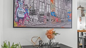 Et moderne interiør med et stort abstrakt maleri, et dekorativt skilt og en vase med blomster på et sort konsolbord.