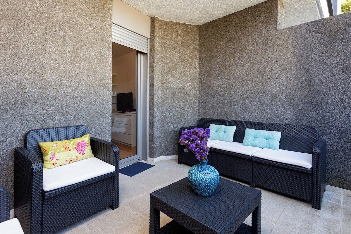 Un espace patio aménagé avec des meubles en osier, une petite table et un vase rempli de fleurs.