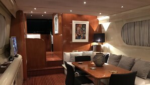 Ein modernes Interieur mit Holzboden, einer Essecke mit Tisch und Stühlen, einer Sofagarnitur und einem Fernseher auf einem Schrank.