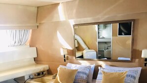 Ein Hotelzimmer mit einem großen Bett, zwei Nachttischen, einem Spiegel und einem Fenster mit Vorhängen.