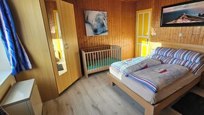 A wooden-paneled room with a bed, a crib, and a painting of a seal.