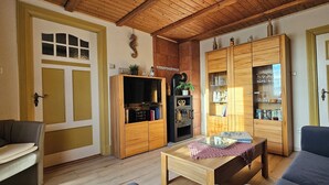 A living room with a wooden ceiling, a sofa, a coffee table, and built-in wooden cabinets with glass doors.
