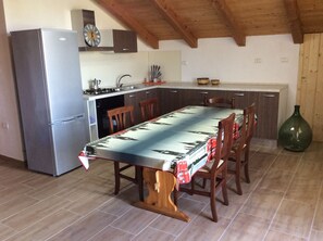 A compact kitchen with a refrigerator, stove, and wooden cabinets. A dining table with chairs is centered in the room. - Rustic villa with private pool (brindisi)
