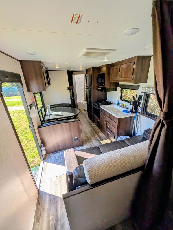 Interior compacto de una autocaravana con kitchenette, zona de comedor y espacio para dormir.