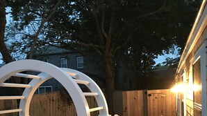 Un patio al aire libre con una pérgola blanca, una parrilla y conjuntos de asientos.