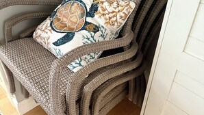 Una silla de mimbre con un cojín estampado, ubicada frente a una pared con suelo de madera.