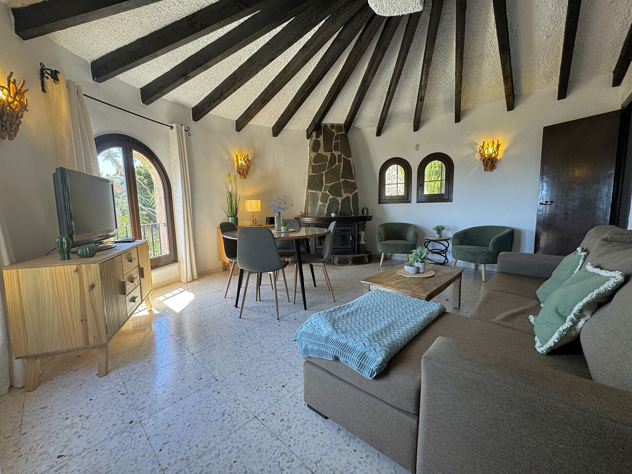 A spacious living area with a stone fireplace, wooden beams, and a cozy seating arrangement.