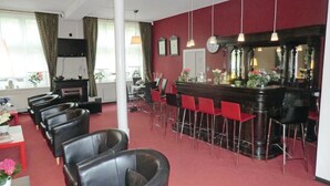 A bar area with a red wall, multiple bar stools, and a counter. There are chairs arranged in the foreground, and a fireplace is visible in the background. - Lovely home in Auerbach with sauna (Auerbach)