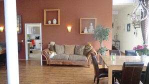 A living room with a brown sofa, a dining table with chairs, and a chandelier. - Lovely home in Auerbach with sauna (Auerbach)