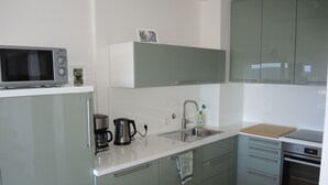 A modern kitchen with a microwave, coffee maker, sink, and oven. - Renovated, bright, light-flooded 4-room apartment (Saig)