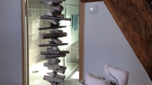 A staircase with a wooden handrail and a white wall with a light switch.