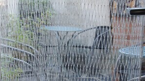 A chain-link fence with a metal gate, a metal table, and a metal chair in the background.