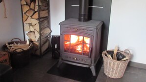 A wood-burning stove with a stone wall and a tiled floor.