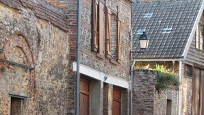 A narrow alley with old brick buildings, wooden doors, and a tiled roof.