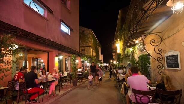 Une rue étroite bordée de terrasses de différents établissements.