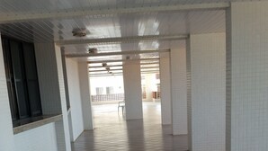 Een ruime, betegelde gang met witte wanden en een hoge plafond.