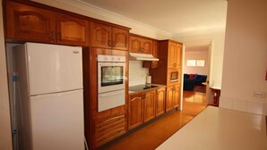 A kitchen with wooden cabinets, a white refrigerator, an oven, and a microwave.