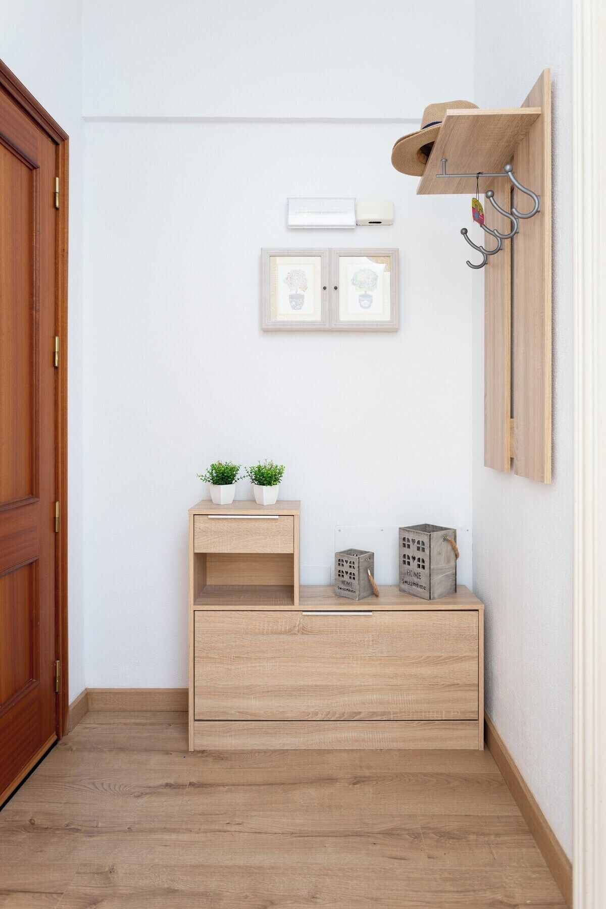 A wooden cabinet with two small potted plants, a framed picture, and a small wooden box with the word "HOME" on it.