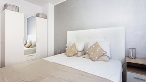 A bedroom with a bed, a wardrobe, a bedside table, and a mirror. - Home2Book Charming Caletillas Pool (Candelaria)