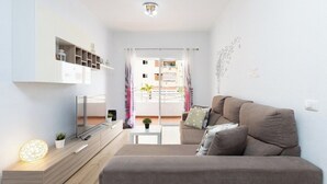 A modern living room with a sofa, TV, and a small table with a plant. - Home2Book Charming Caletillas Pool (Candelaria)