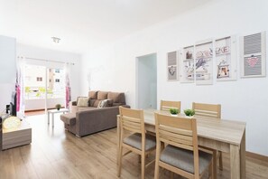 Una sala moderna con un sofá, una mesa de comedor con sillas y un televisor sobre un mueble.