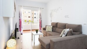 A modern living room with a sofa, a small table, a lamp, and a view of the outside balcony. - Home2Book Charming Caletillas Pool (Candelaria)