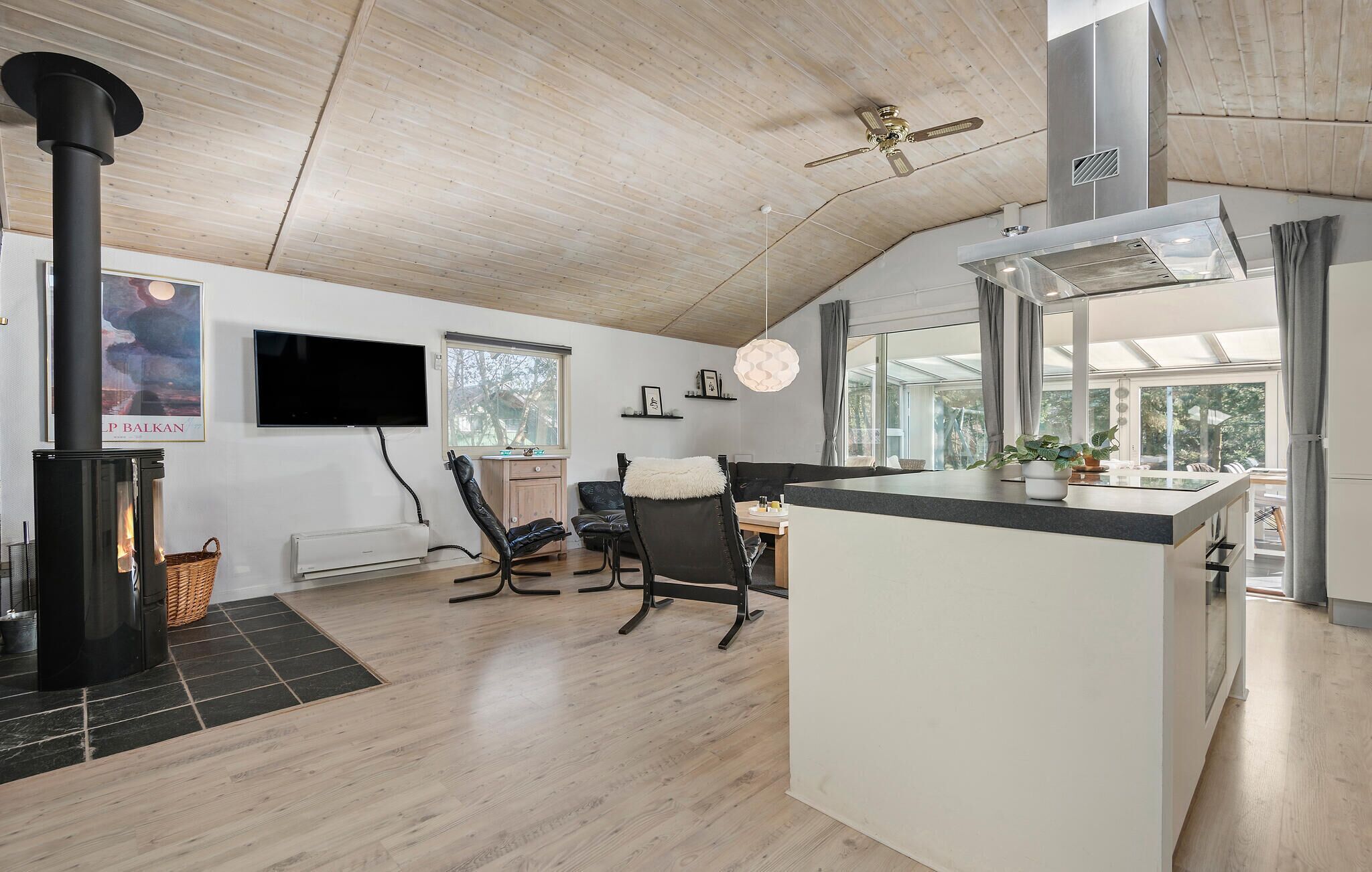 Una cocina moderna con una isla central, un comedor con sillas, una chimenea y un ventanal que proporciona luz natural.