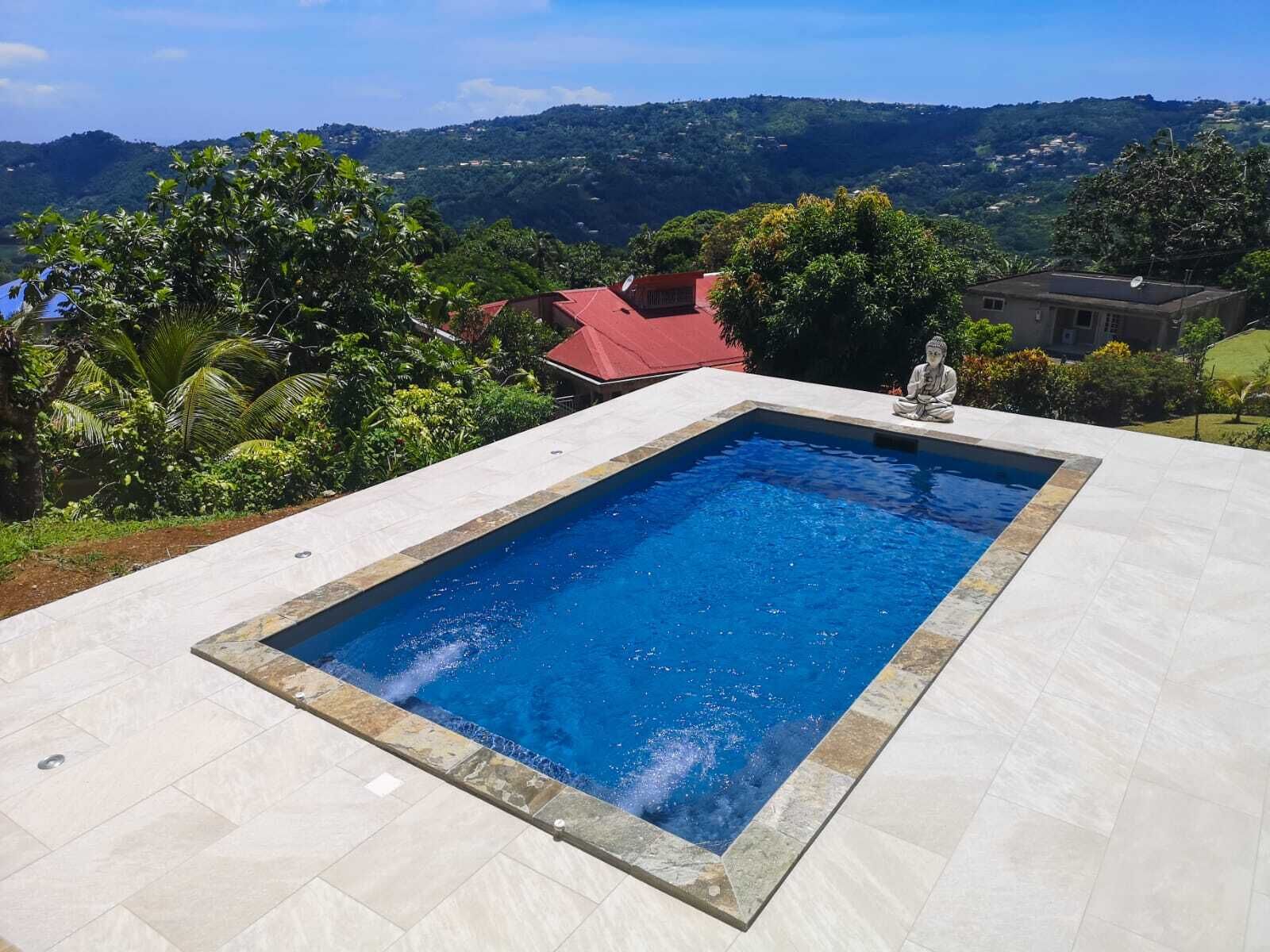 A rectangular swimming pool with a clear blue water, surrounded by a tiled deck.