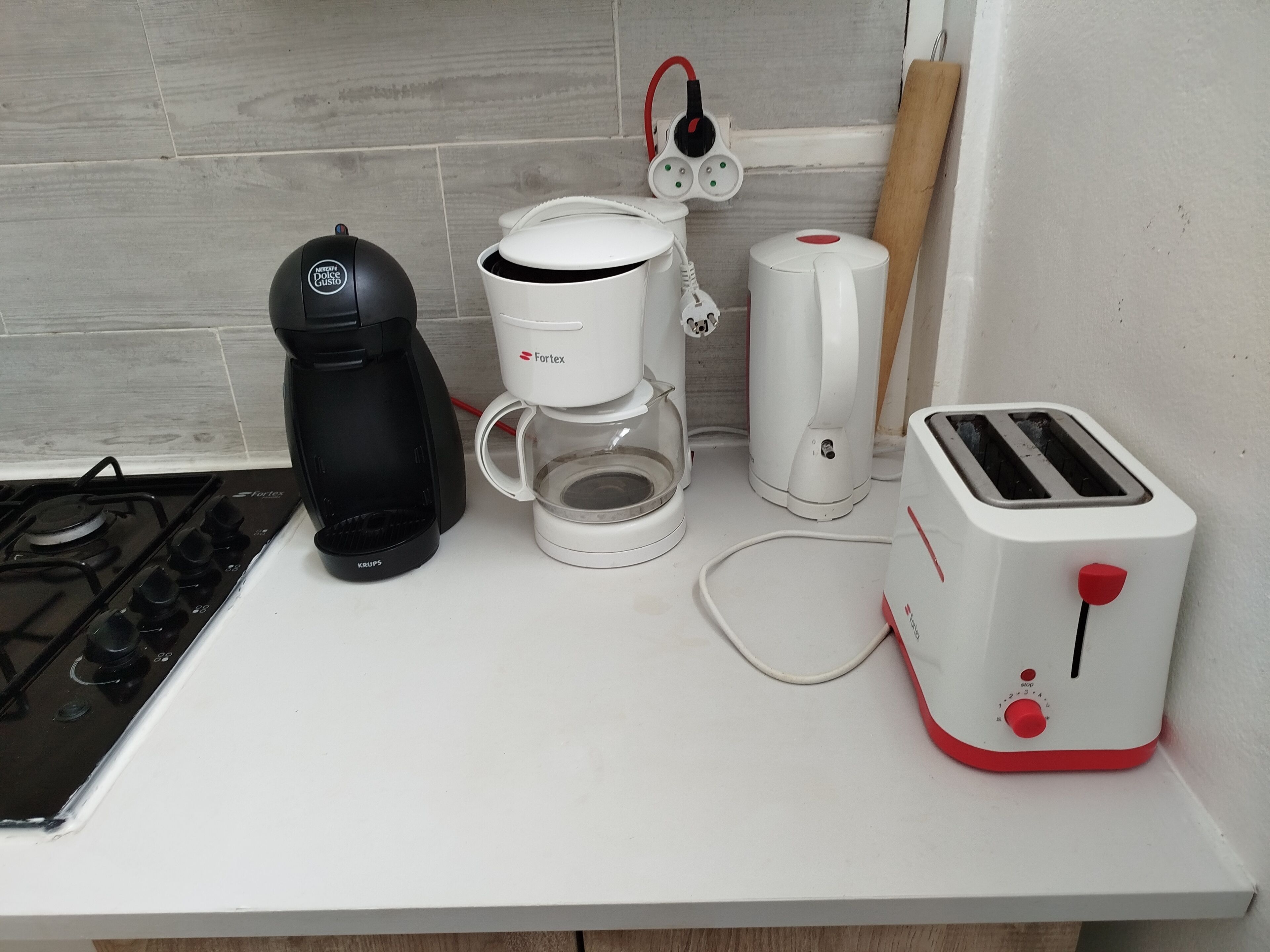 A kitchen with a gas stove, a coffee maker, a toaster, and a kettle.