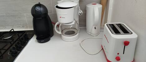 A kitchen with a gas stove, a coffee maker, a toaster, and a kettle.