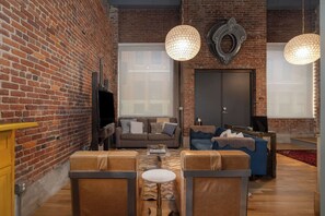 A living room with brick walls, leather sofas, a coffee table, and pendant lights.