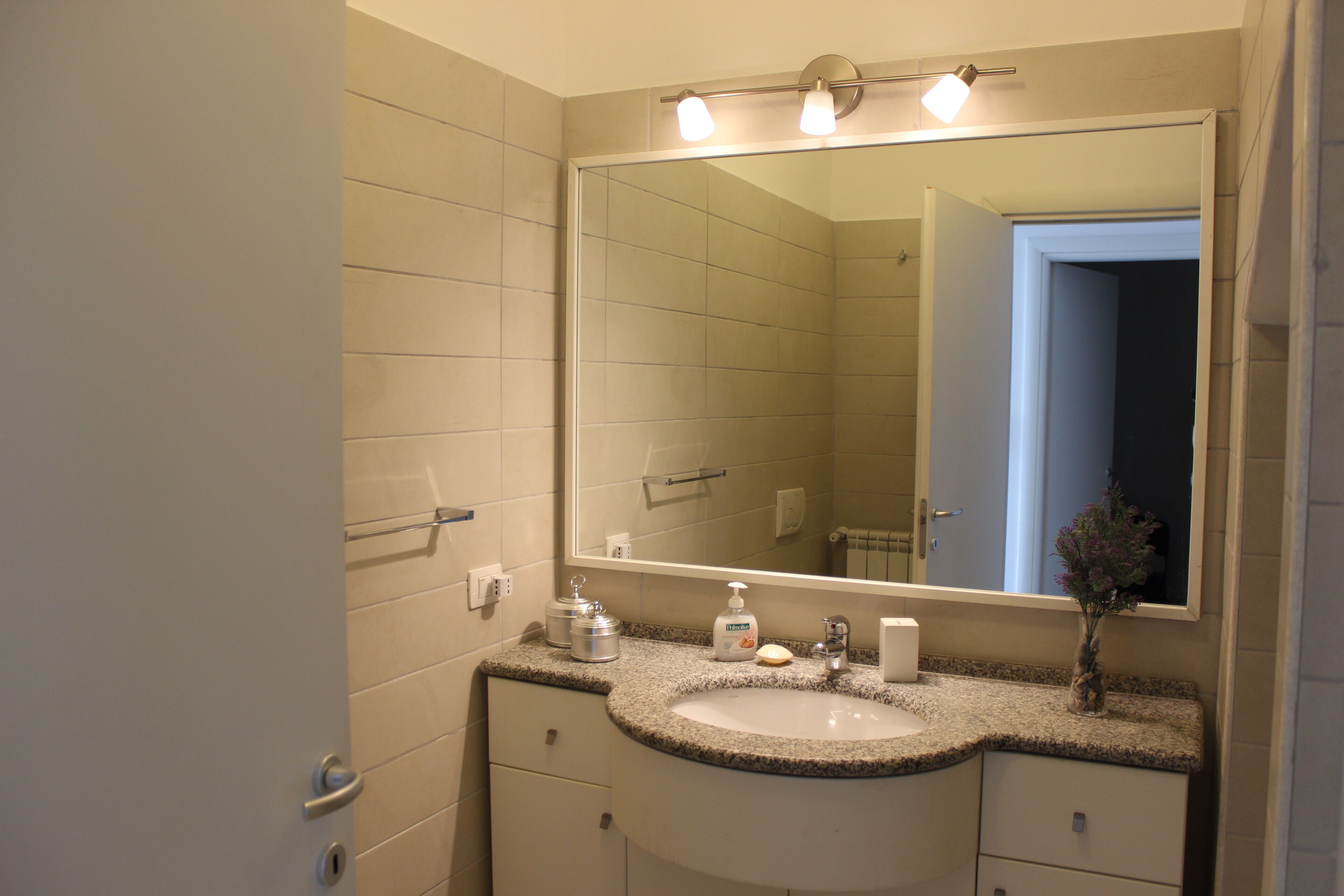 A bathroom with a large mirror, a sink, and a vanity with cabinets.